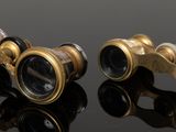 pair of antique brass binoculars on black surface with reflection