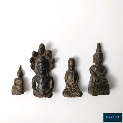 cinq petites statues de bouddhas posées sur une surface blanche