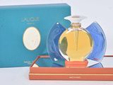 une image représentant un flacon de parfum posé sur une boîte bleue