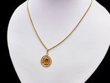a gold necklace with an orange stone on a white mannequin