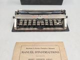 une vieille machine à écrire manuelle posée sur une table, à côté d'une boîte