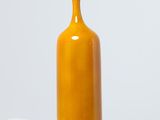 un vase jaune posé sur une table blanche
