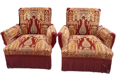 pair of upholstered chairs with red fringes on them