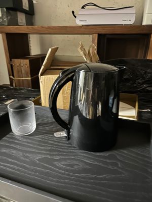 une cafetière noire posée sur un plan de travail, à côté d'un verre d'eau
