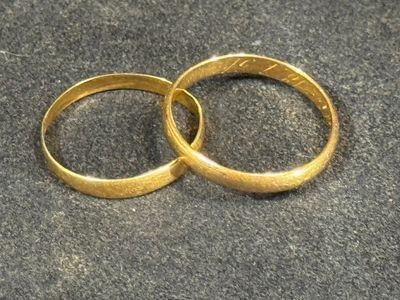 two gold wedding rings sitting on a black surface