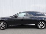 La Volvo break noire est garée devant un immeuble blanc.