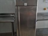a stainless steel refrigerator in a kitchen with a table in the background