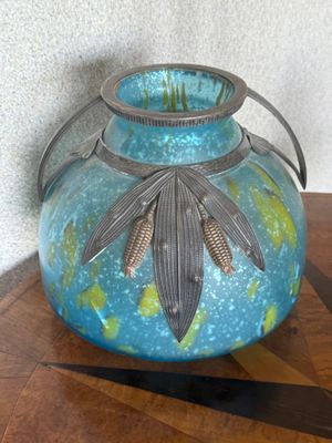 un vase bleu orné d'une feuille, posé sur une table