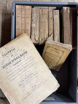 une boîte pleine de vieux livres posée sur le sol