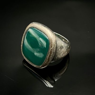 un gros plan d'une bague ornée d'une pierre verte sur un fond noir