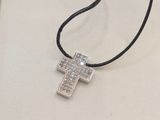a silver cross on a black cord necklace on a book