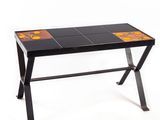 une photo d'une table carrelée de noir et d'orange, avec un piètement en métal