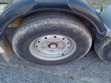 a flat tire on a trailer that is parked on the side of the road