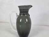 a green glass pitcher with a handle on a table