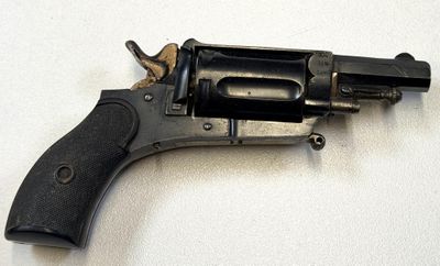 un vieux revolver posé sur une surface blanche, avec une crosse noire