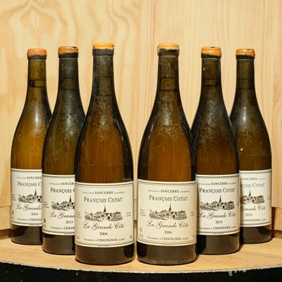 six bottles of wine are lined up on a wooden shelf