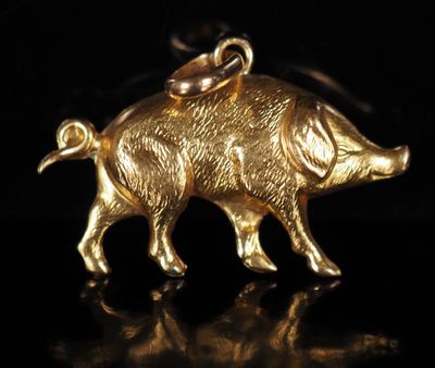 un gros plan d'un pendentif en forme de cochon doré sur fond noir