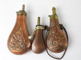 three antique brass bottle shaped like lamps on a white surface