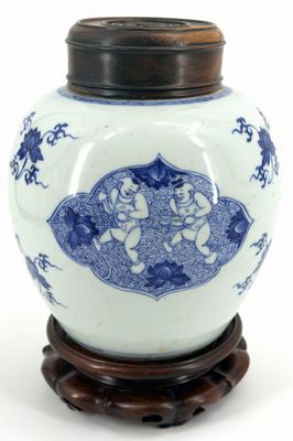 a blue and white vase with a lid on a wooden stand