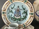 a plate with a picture on it next to a cup and saucer