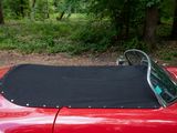 a red sports car with a black top parked in the woods
