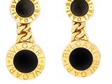 Les boucles d'oreilles dorées et noires sont mises en valeur sur un fond blanc.