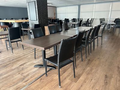 des tables et des chaises dans une grande pièce avec un parquet et des murs blancs