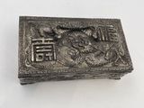 silver metal box with a dragon on it on a white surface