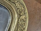a gold frame with a clock on it on a table