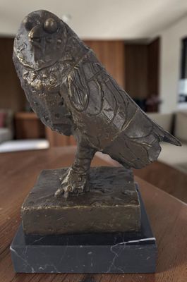 une statue représentant un oiseau perché sur une table en bois