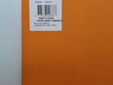 an orange book sitting on top of a wooden table next to a white wall
