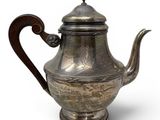 an old silver teapot with a wooden handle on a white background
