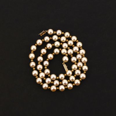 a gold pearl necklace on a black background