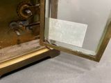 a gold clock with a glass door and a sign on it