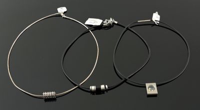 paire de boucles d'oreilles créoles en argent avec un cordon en cuir noir et des breloques en argent