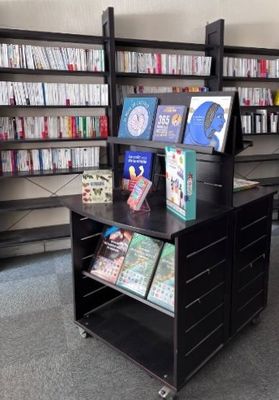 un présentoir noir sur lequel sont posés des livres, dans une bibliothèque