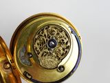 a close up of a gold pocket watch with a blue stone