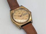 une image d'une montre sur une surface blanche avec un bracelet marron