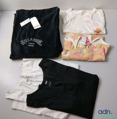 Trois t-shirts sont posés sur une table, accompagnés d'une étiquette de prix
