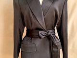 La veste est noire et comporte une ceinture à nouer à la taille.