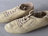 pair of beige leather shoes with laces on them on a gray surface
