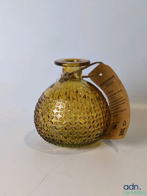 un petit vase en verre jaune sur lequel est accrochée une étiquette