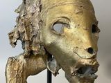 gold sculpture of a woman ' s head on a black stand