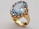 a close up of a ring with an oval blue topaz stone