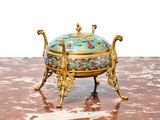 a gold and blue bowl on a stand on a marble surface