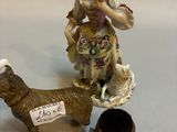 a figurine of a woman and a dog next to a cup