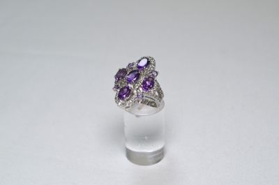 a close up of a ring with purple stones on a white surface
