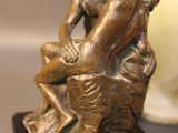a bronze statue of a man and a woman sitting on a tree stump