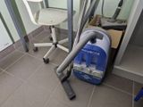 un aspirateur posé sur le sol à côté d'une chaise