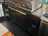 plan de travail en acier inoxydable dans une cuisine professionnelle équipée d'une cuisinière et d'un réfrigérateur